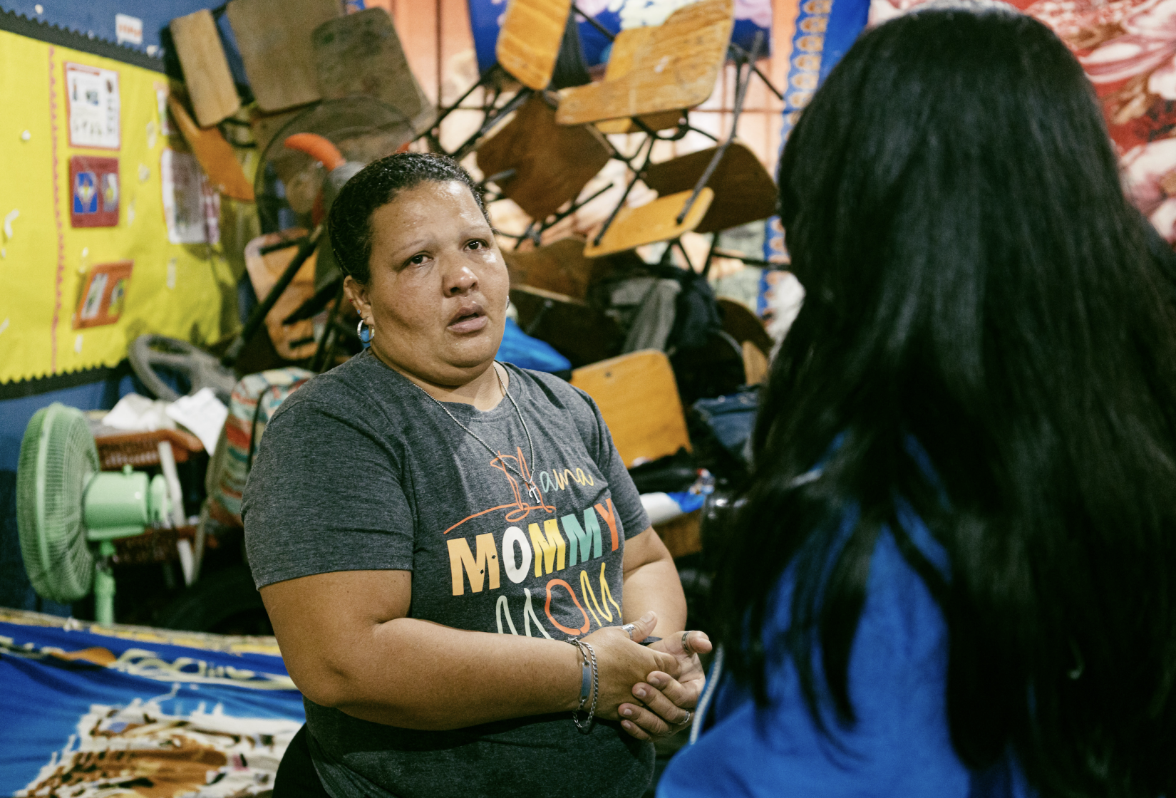 Una madre en un albergue temporal dialoga con una persona sobre la situación que vivió por la inundación.