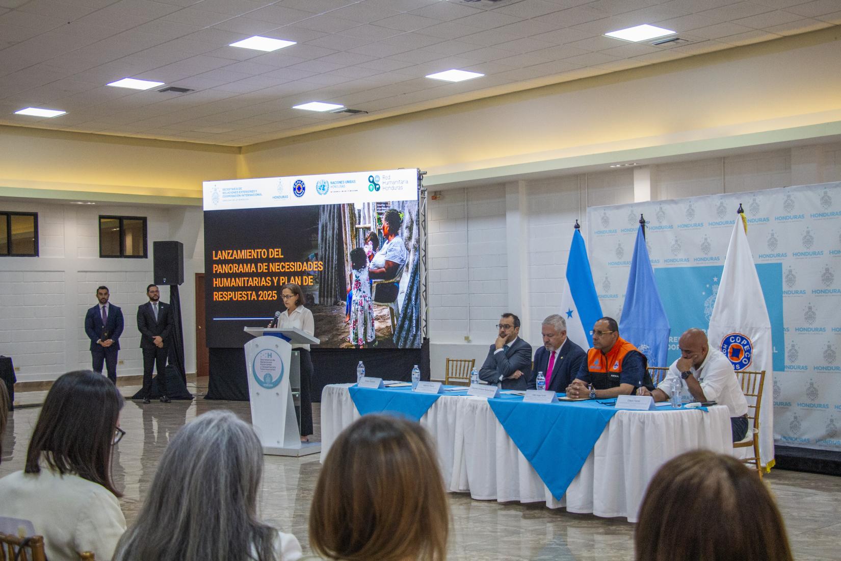 salón de conferencias, donde se está llevando a cabo el lanzamiento del Panorama de Necesidades Humanitarias y Plan de Respuesta 2025 en Honduras. mesa principal y representante de OCHA en el podio