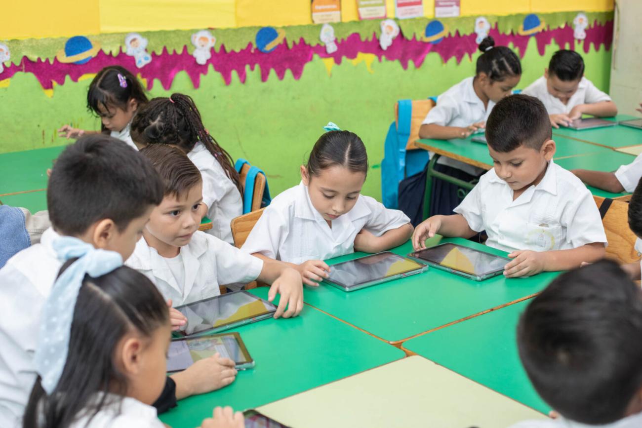 Niños y Niñas con tablets en un salón de clases 