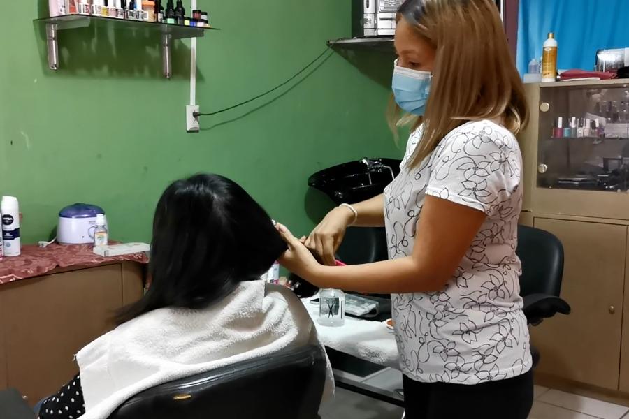 Jenny peina a una mujer en su salón de belleza.