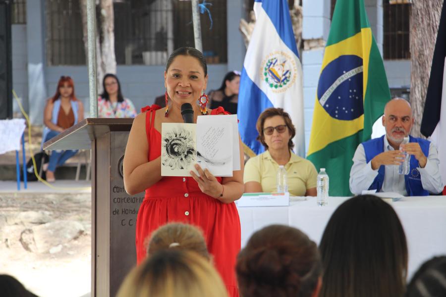 Mujer muestra un libro donado y su dedicatoria.