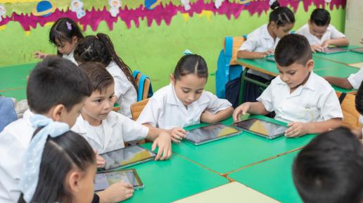 Niños y Niñas con tablets en un salón de clases 