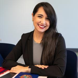 Foto de María Elena Calix viendo hacia cámara con sus brazos sobre una mesa