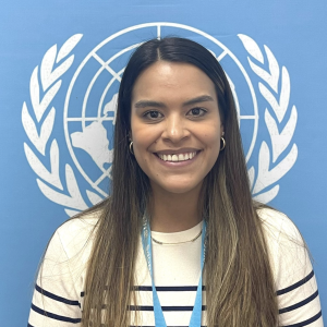 Laura sonríe a cámara frente a un logo de Naciones Unidas